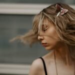 Artistic portrait of a woman with hair in motion and a butterfly clip, capturing style and motion.